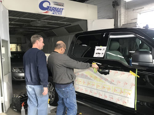 two men measuring decals on a black truck